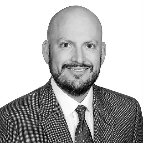 Smiling bald man with beard in suit and tie.