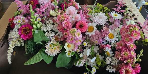A vibrant bouquet of pink, white, and yellow flowers with lush green leaves.