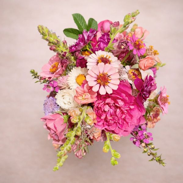 A vibrant bouquet of various pink, purple, and white flowers with green leaves.