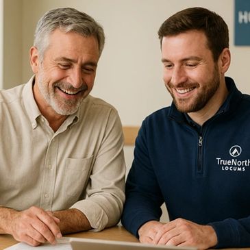 Two men smiling and looking at a tablet together.