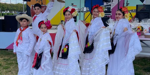 Children dressed in traditional Mexican folkloric attire posing outdoors.