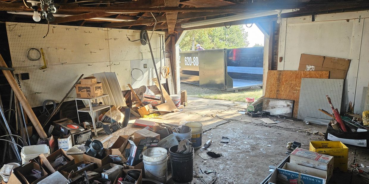Cluttered garage with scattered tools and open garage door.