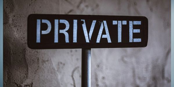 A metal 'PRIVATE' sign against a textured wall.