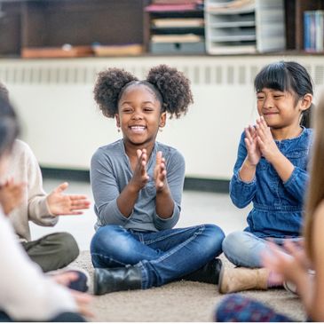 two young girls clapping during a music therapy group