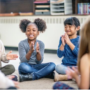 two young girls clapping during a music therapy group
