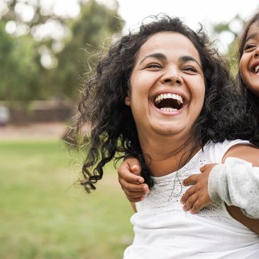 A mum laughing. Her child is on her back