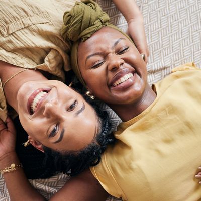 two women lying down with their heads together, smiling