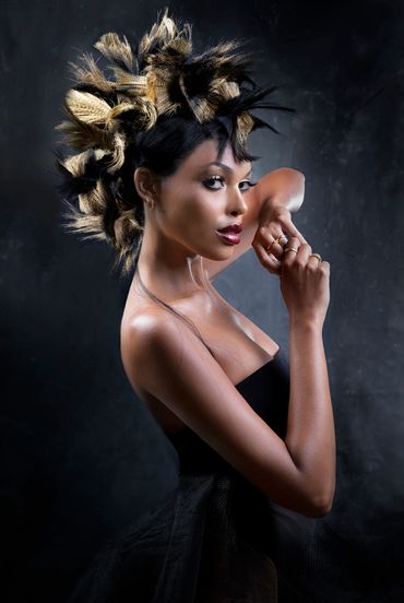 Woman with artistic spiked hairstyle and elegant black dress posing confidently.