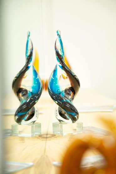 Elegant glass sculpture with blue and black swirls, reflected on a mirror.