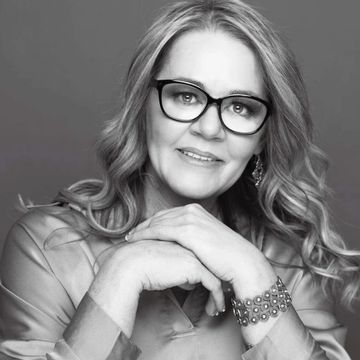 Mature woman with glasses smiling gently.