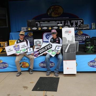 Two men holding fishing competition awards on stage.
