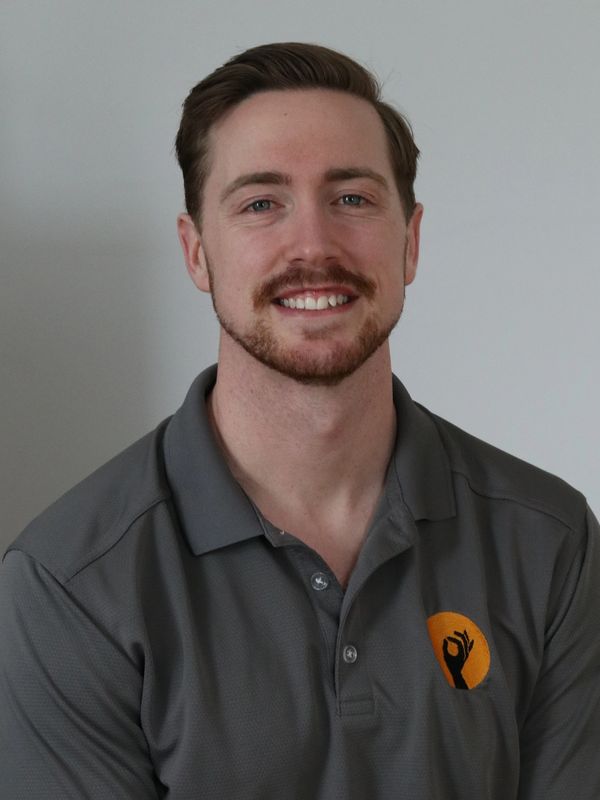 Smiling man with tattoo wearing gray polo shirt.