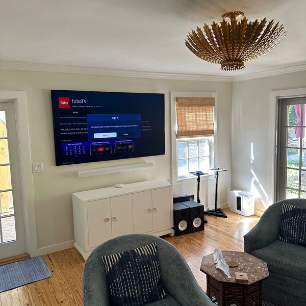 Cozy living room with a mounted TV, blue armchairs, and a decorative wooden table.