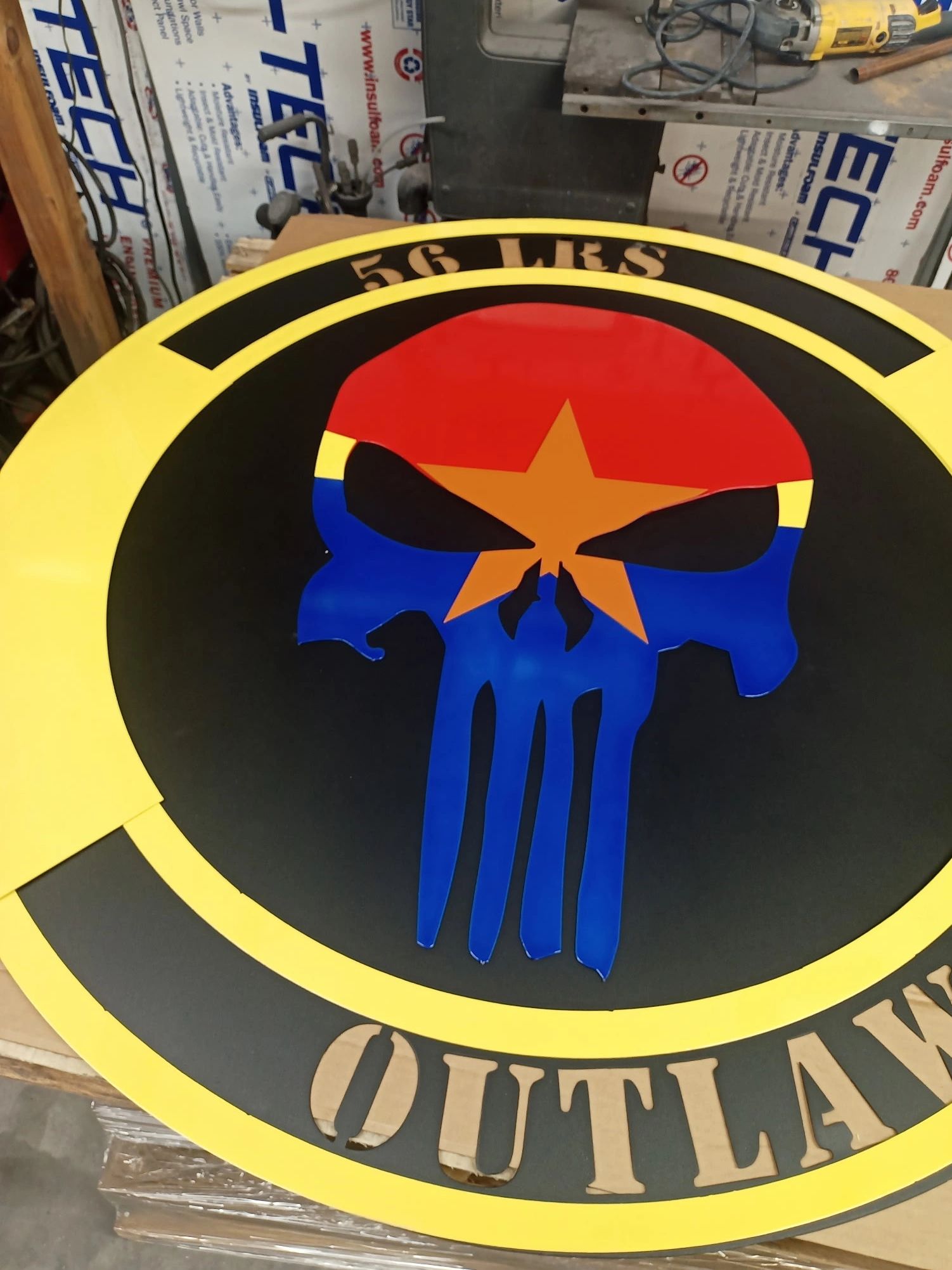 A colorful skull emblem with yellow border and text.