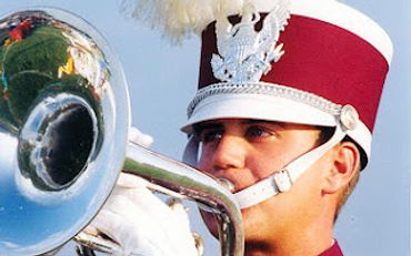 A marching band member playing a brass instrument in uniform.