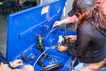 Estudiantes del taller de mecánica para mujeres limpiando partes del sistema de frenos. ©CESFOM 2023