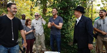 Group of people smiling and interacting outdoors in a wooded area.