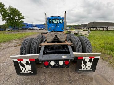 Rear view of a blue semi-truck tractor with dual tires and mud flaps.