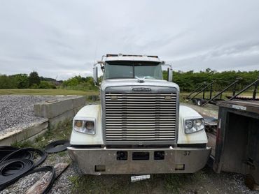 Front view of a white Freightliner semi-truck parked outdoors.