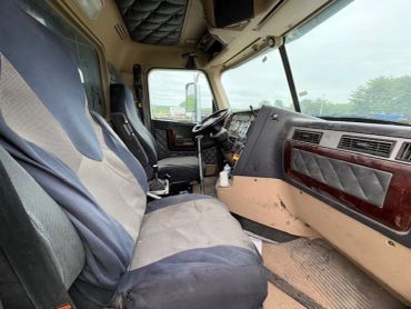 Interior view of a truck cabin with two seats and a dashboard.