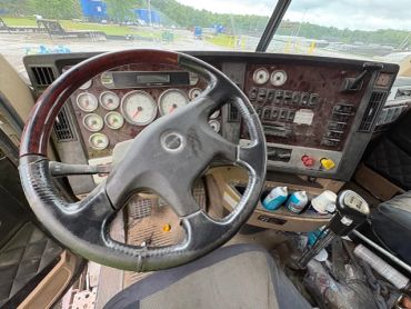 Interior view of a truck cabin showing steering wheel and dashboard.
