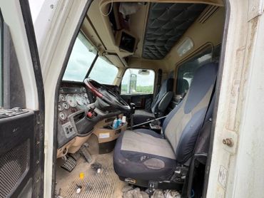 Interior of a truck cabin showing worn seats and dashboard.