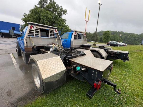 Two blue semi-truck tractors parked on grass and pavement under an overcast sky.