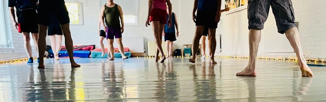 Group of people standing barefoot in a bright indoor space with reflective flooring.