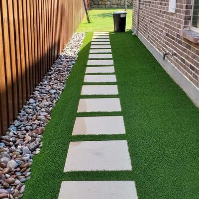Stone path with grass and rocks beside a house.