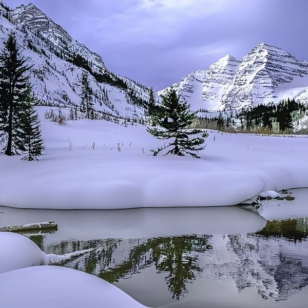Snow-covered mountains and pine trees reflected in a calm river.