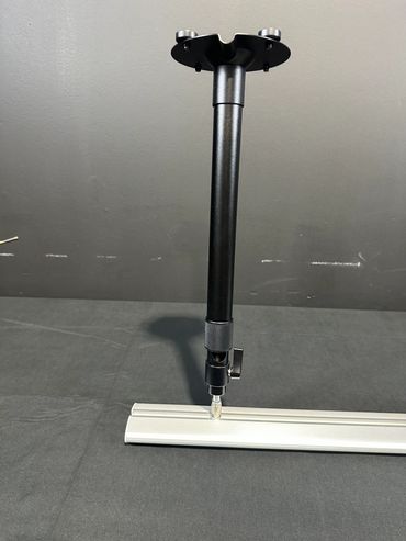 Adjustable black metal support leg attached to a white base on a gray surface.