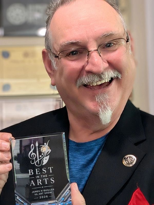 Man holding a Best in the Arts award with a big smile.