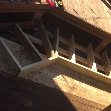 Wooden staircase under construction with sunlight casting shadows.