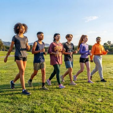 A group of diverse teenagers walking outdoors on grass.