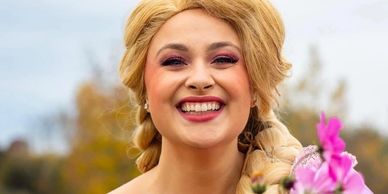 Smiling woman with braided blonde hair and flowers.