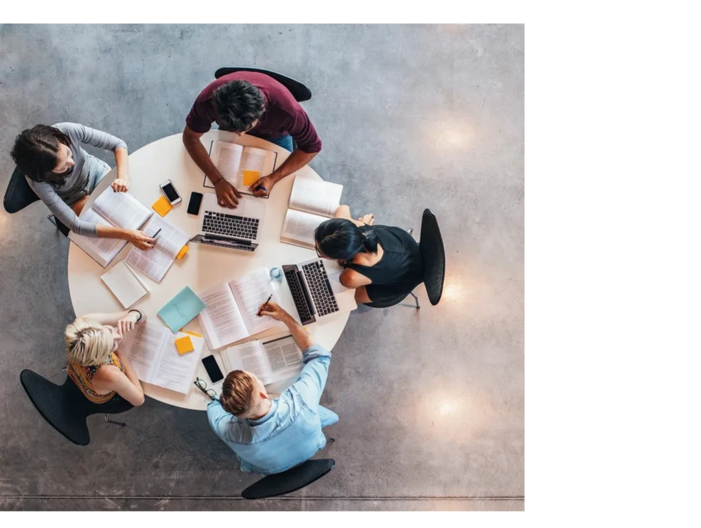 Business professionals working sitting at a round table with documents, books and laptops 