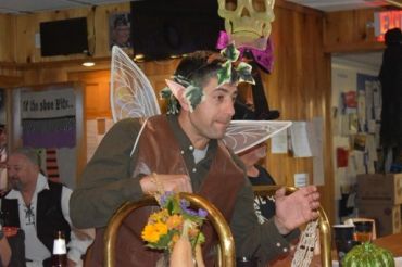 Man dressed as a fairy at a festive indoor event.