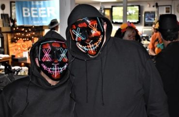 Two people wearing black hoodies and neon light masks.
