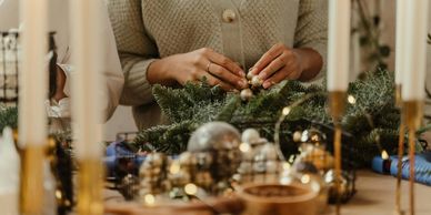 Person decorating a Christmas wreath with ornaments.