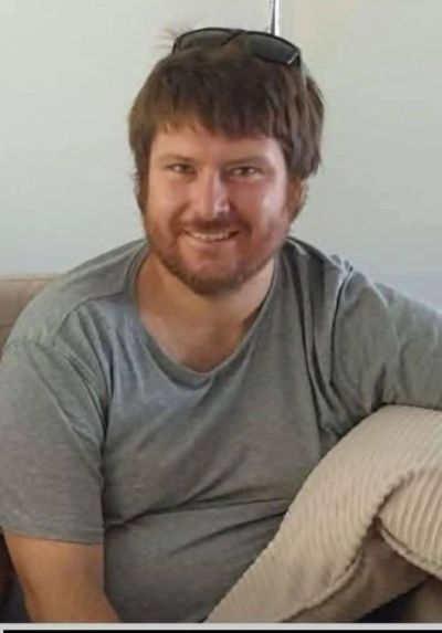 Smiling man sitting with sunglasses on his head.