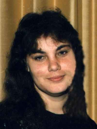Portrait of a woman with dark hair against a curtain background.