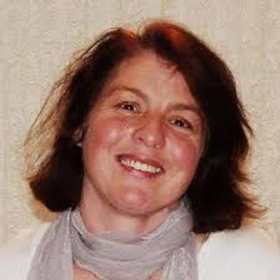 Smiling woman with dark hair and a light scarf.
