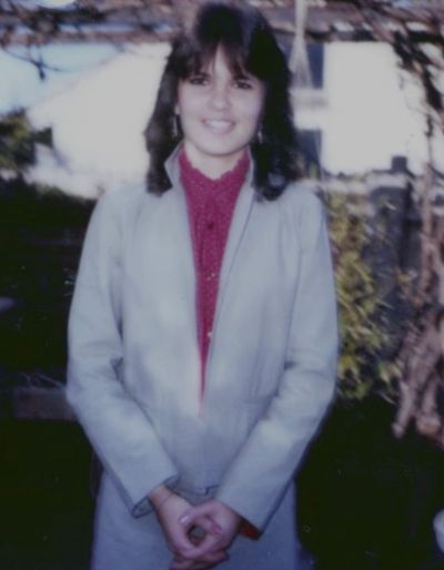 Young woman smiling outside wearing a light gray jacket.