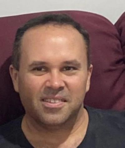 Man smiling while sitting on a maroon couch.