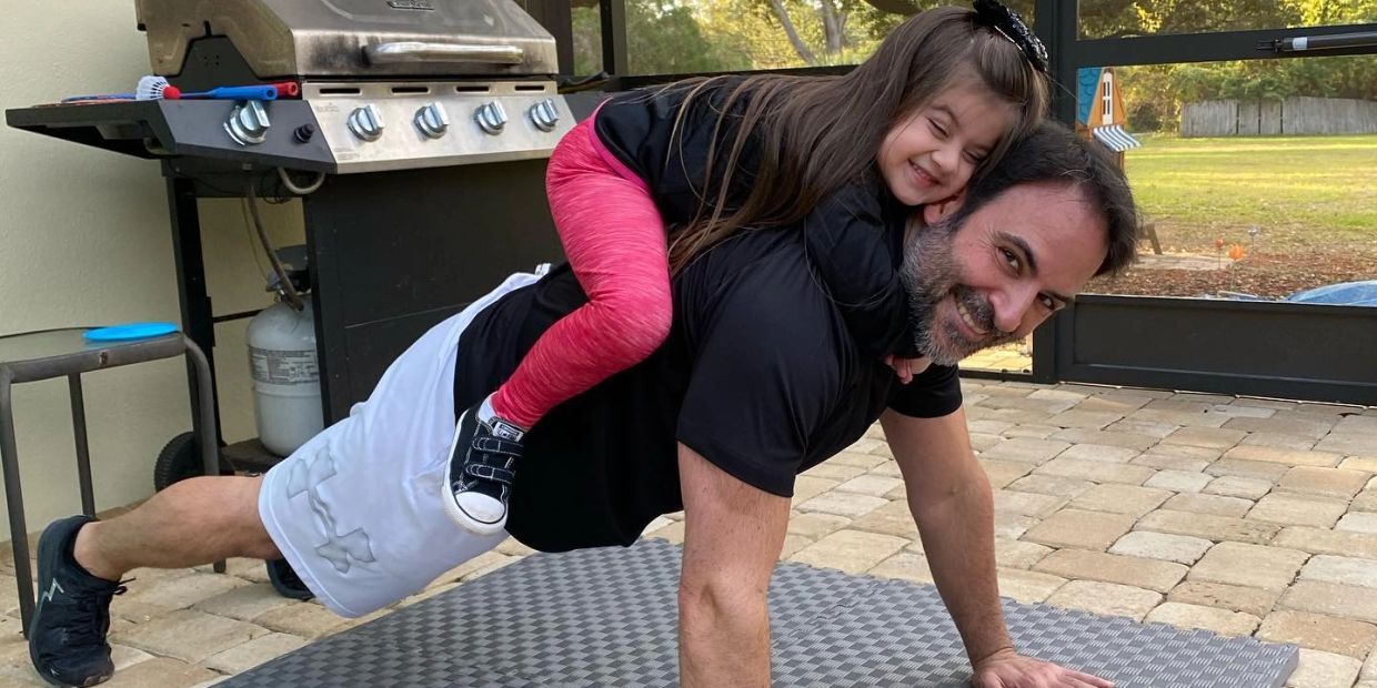 Man doing push-ups with a smiling child on his back.