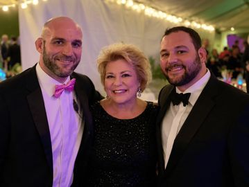 Three people dressed formally, smiling.