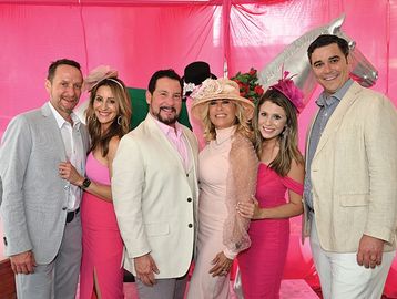 Group of six people dressed in pink and white at an event.