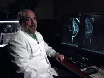 Doctor reviewing medical scans in a dark room.