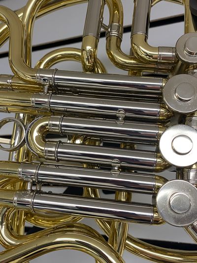 Close-up of a brass French horn with intricate tubing and valve keys.