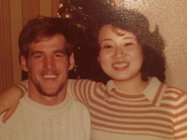 Smiling couple in cozy sweaters posing closely indoors.